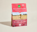 Dog food package with a red label featuring a cow and field on a beige background