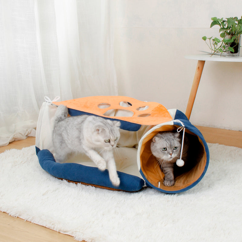 Two cats playing with a tunnel toy on a white rug.