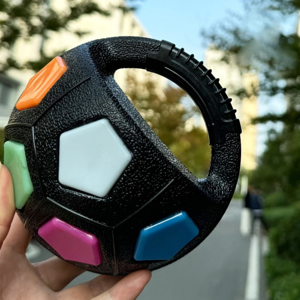 Black textured ball with colorful buttons held outdoors
