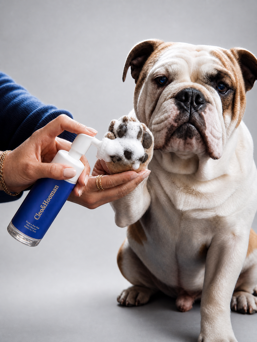 Person applying a product to a dog's paw with a gray background