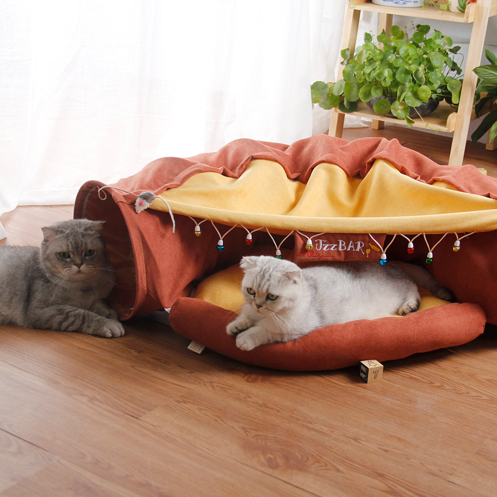 Two cats playing with a tunnel toy on a wooden floor.