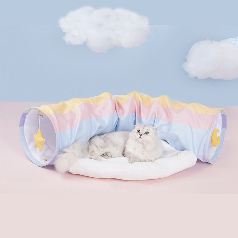 Cat lying on a pastel-colored pet tunnel with clouds in the background