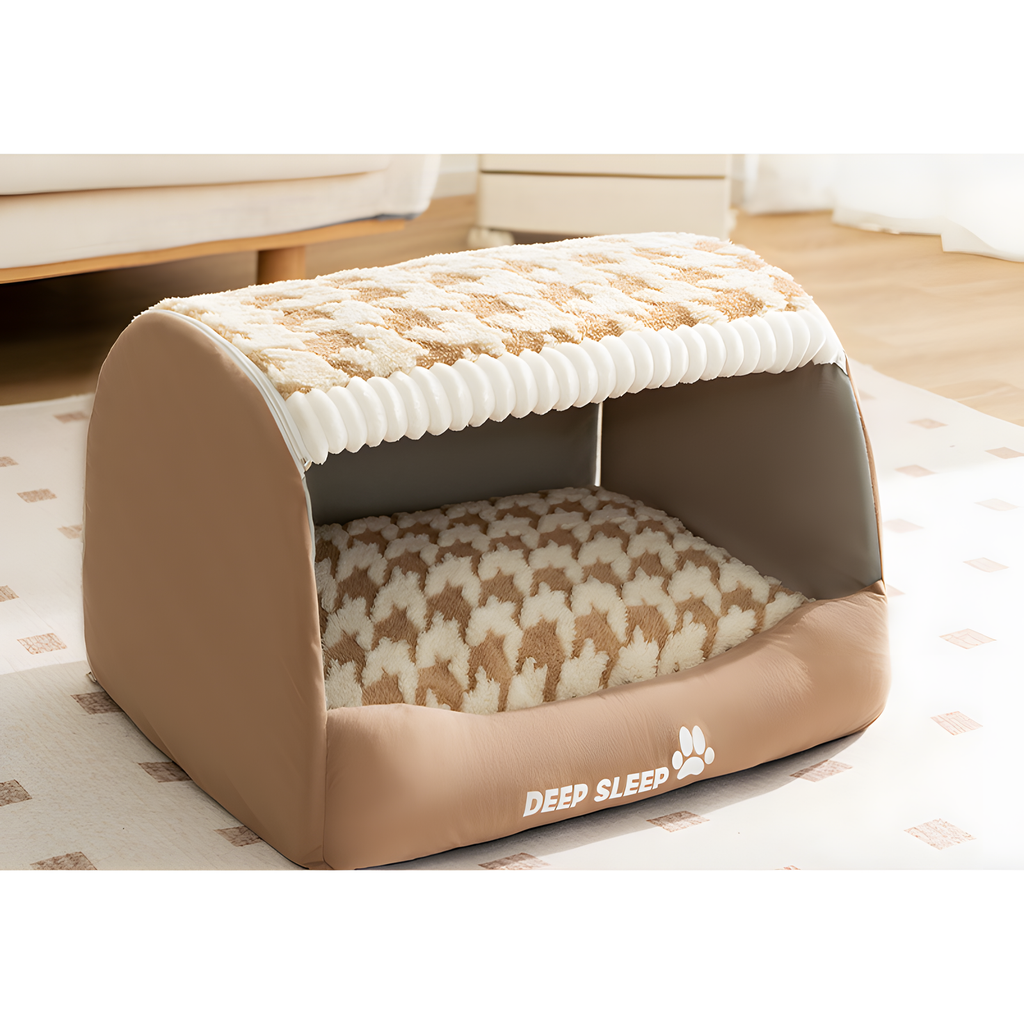 A tan and cream pet bed with a ribbed fabric roof and a patterned cushion inside, shown on a patterned rug in a softly lit room. The front edge reads 'DEEP SLEEP' with a small paw print.